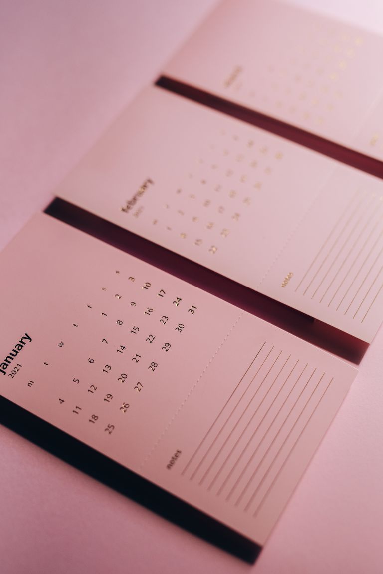 From above of paper calendar with titles and horizontal lines on table in pink light